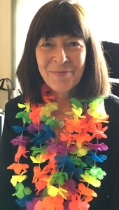 Photograph of Claire Clancy wearing a rainbow garland to prepare for Pride Cymru